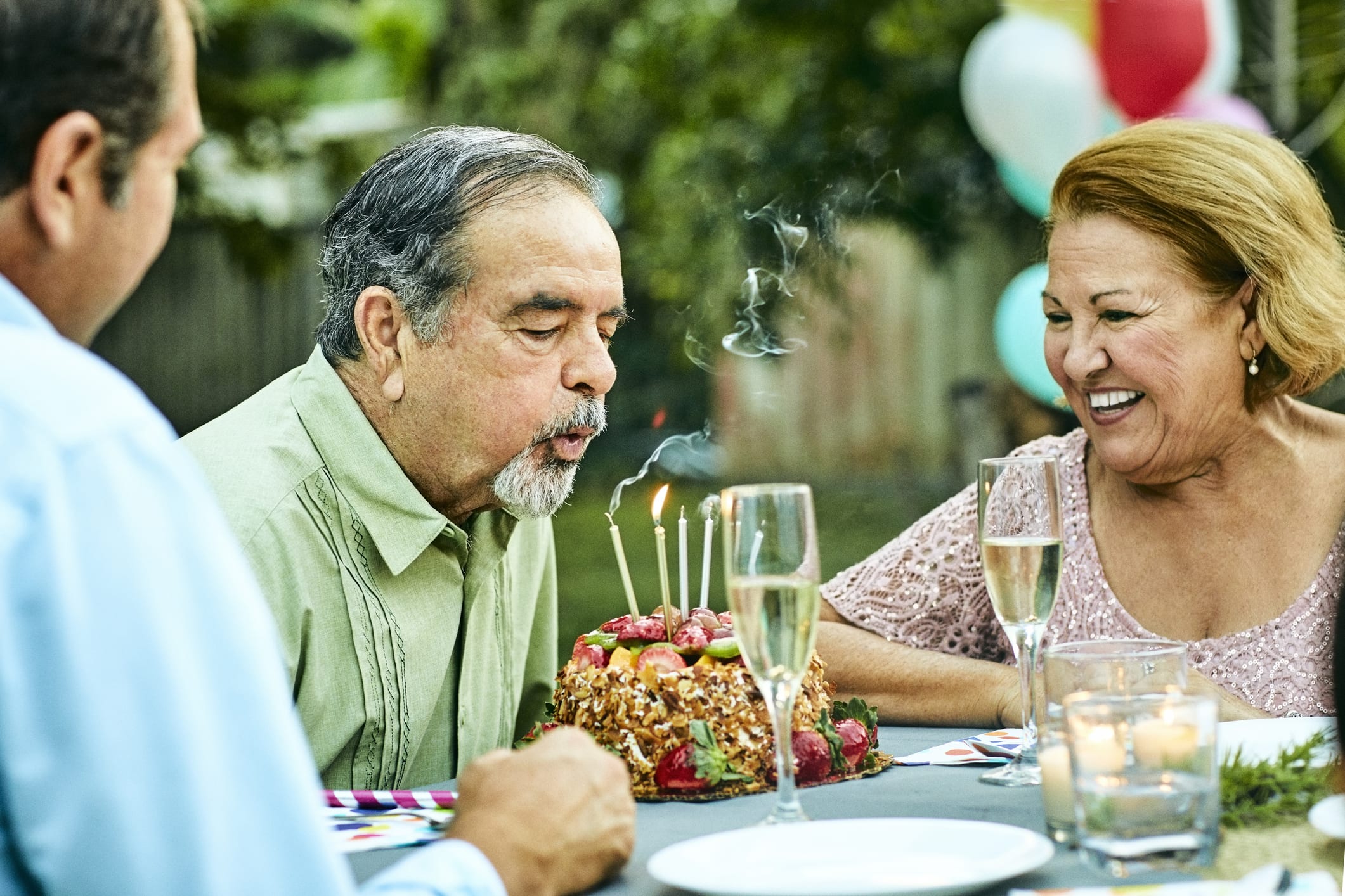 Senior Woman Looking At Man Blowing Birthday Candles