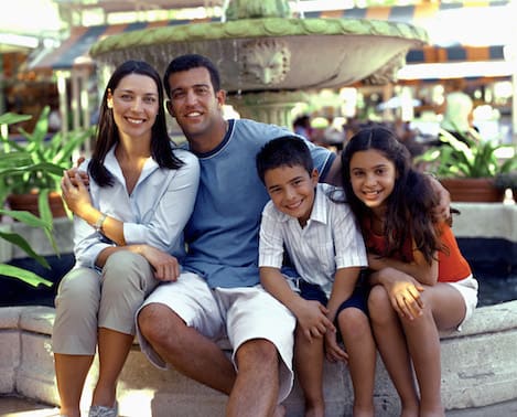 Family of four smiles by fountain 