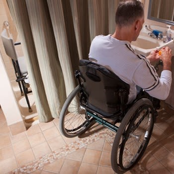 Man uses wheelchair in bathroom remodeled for accessibility