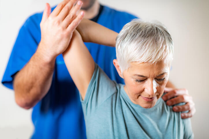 A chiropractor pulls a woman's arm back in a stretch