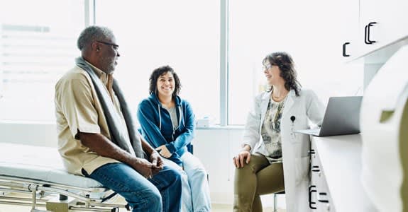 Doctor speaks with smiling couple in doctor's office
