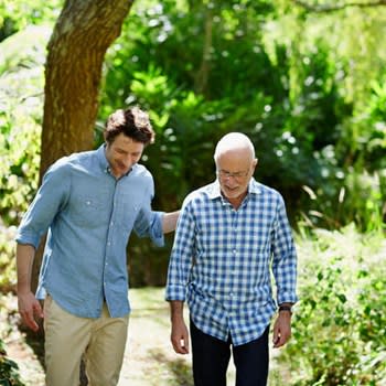 Man walks through outdoor park with caregiver