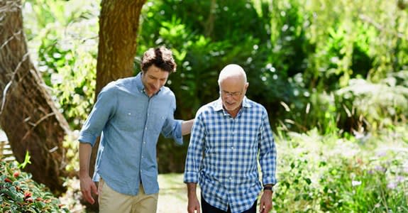 Man walks through outdoor park with caregiver
