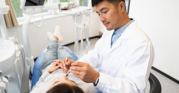 Dentist examines patient in dentist chair