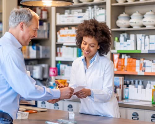 Pharmacist gives prescription to patient at drug store