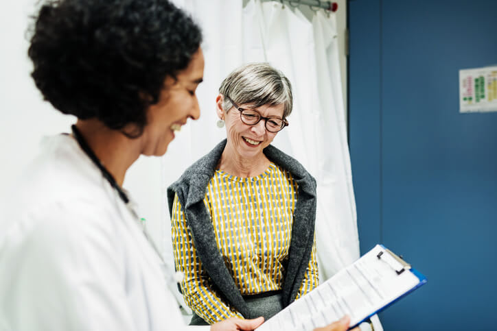 Smiling doctor reviews medical information with happy patient