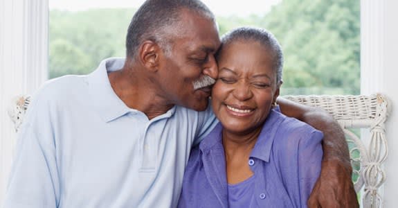 Man kisses his smiling wife on her cheek