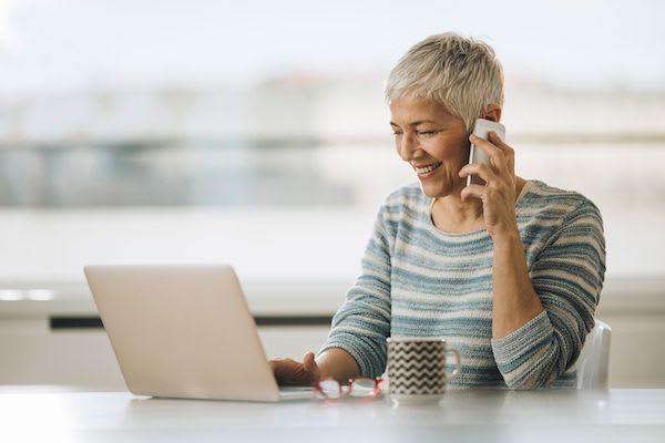 Woman on her phone while at the computer