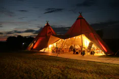 Blick von aussen am Abend auf ein halb offenes Tipi