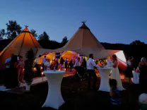 Hochzeitsfest im Tipi mit einigen Gästen an den Stehtischen