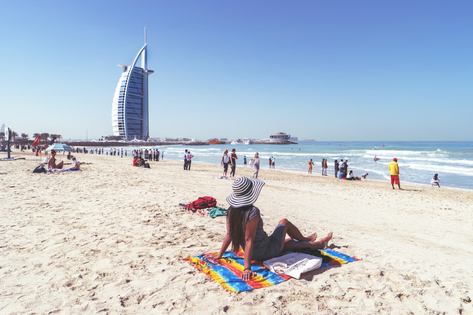 What to do in Dubai - Tourist at Jumeirah Beach, looking at Dubai’s iconic sail-shaped hotel, Burj Al Arab