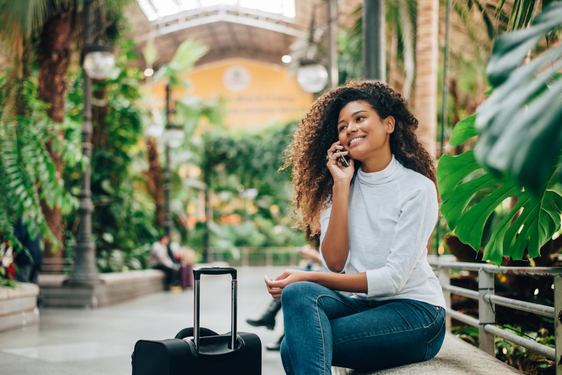 Young traveller with luggage talking on phone - 7 INTERNATIONAL TRAVEL FACTS: A Simple Guide to a Smooth Trip - International Travel Tips - Travel facts