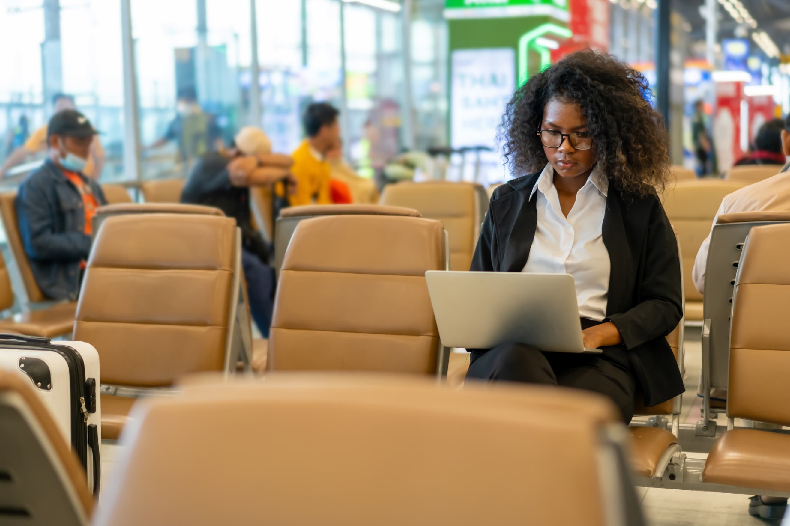 Confident African business woman and entrepreneur using airport wi-fi while waiting to check-in at airport terminal - 7 INTERNATIONAL TRAVEL FACTS: A Simple Guide to a Smooth Trip - International Travel Tips - Travel facts