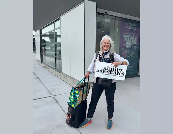 A friendly woman holding an "ability adventures" sign