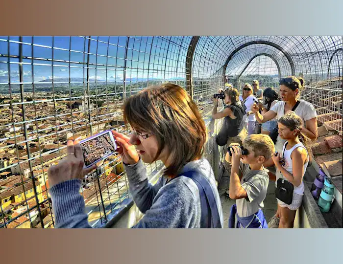 Tourists taking photos from a caged lookout over a European city