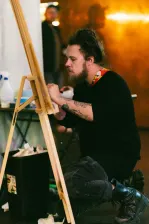 A side on photo of an artist painting on a canvas