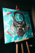 A stencil of an astronaut helmet on a canvas with blue decorative background