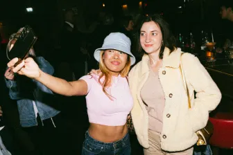 A woman wearing a blue hat taking a selfie with another woman