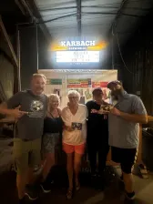 Jon Beardmore in an outdoor bar with four people. Two people are holding a postcard he has delivered to them.