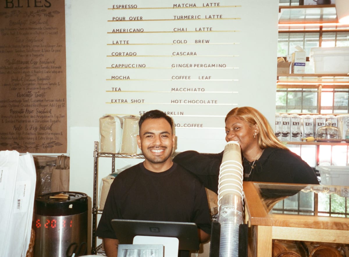 Two smiling baristas behind the counter at Afficionado Coffee