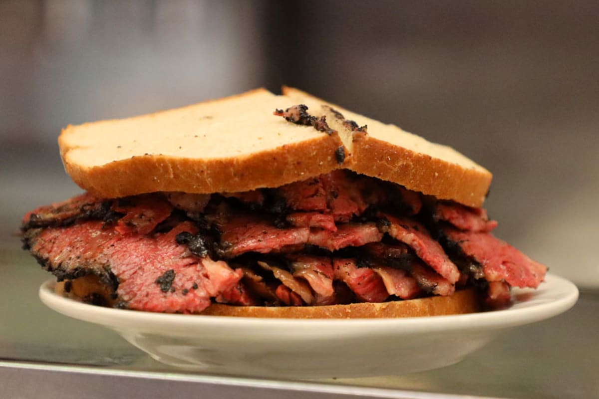 Pastrami sandwich on white plate.