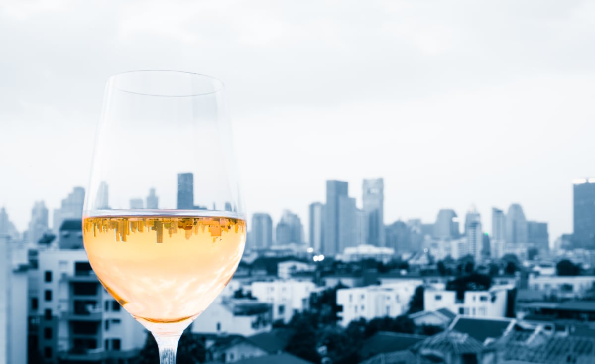 Black and white photo of new york with a colored glass of wine in the foreground, reflecting an mirror image of the skyline in the wine