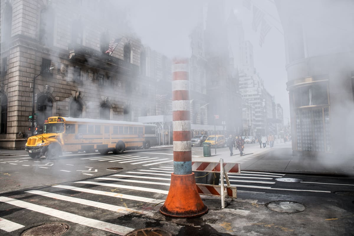 steam stacks in new york outside subway station with city in the background