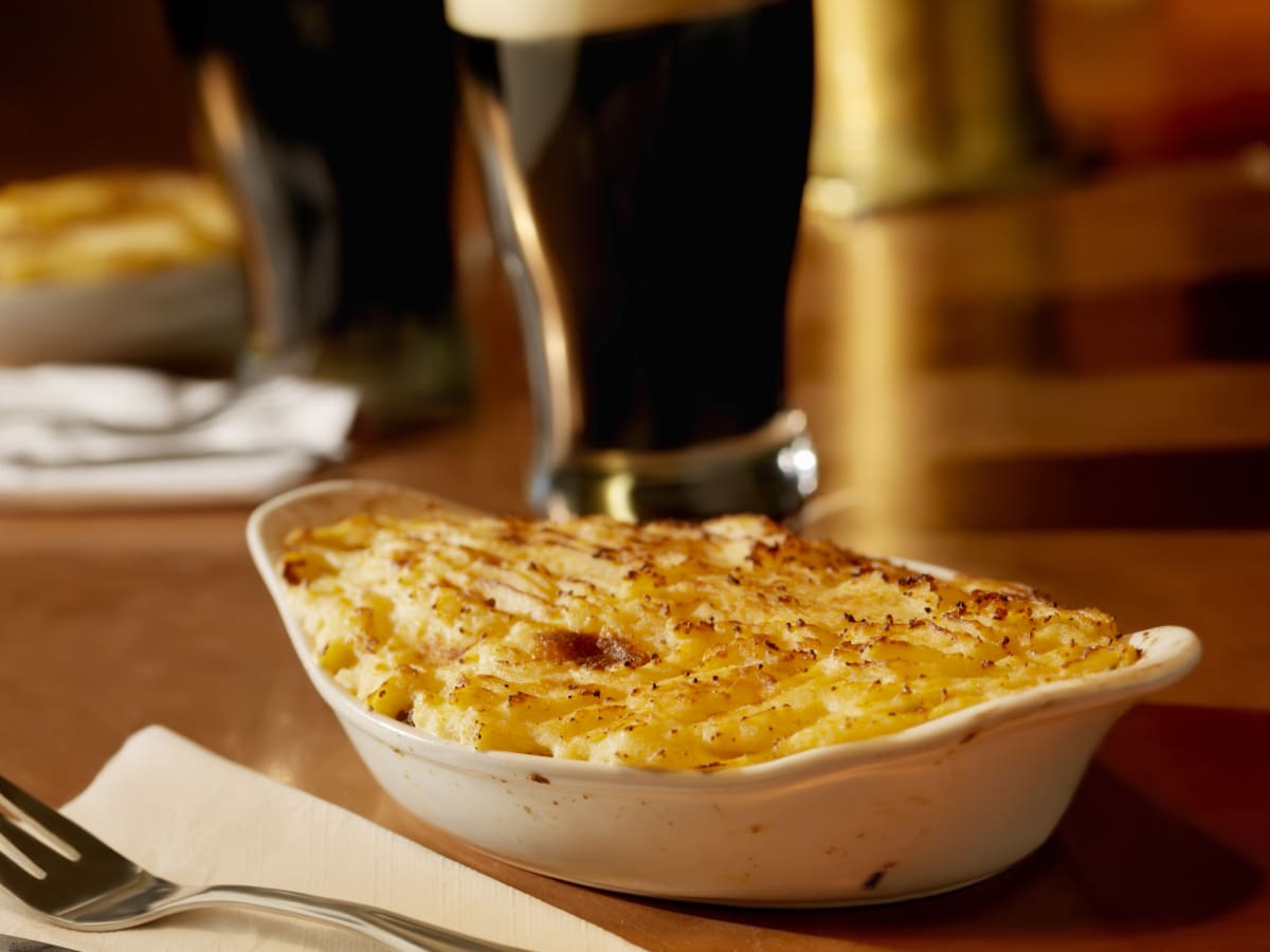 Traditional cottage pie topped with mashed potato with an irish style beer in the background