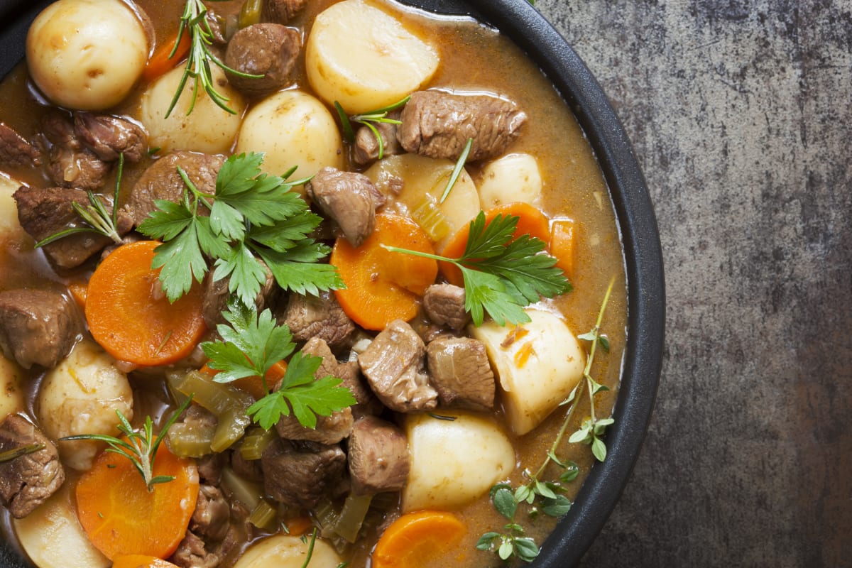 Traditional irish meat stew, with carrots, potatoes and parsley, served in a broth on a black plate 