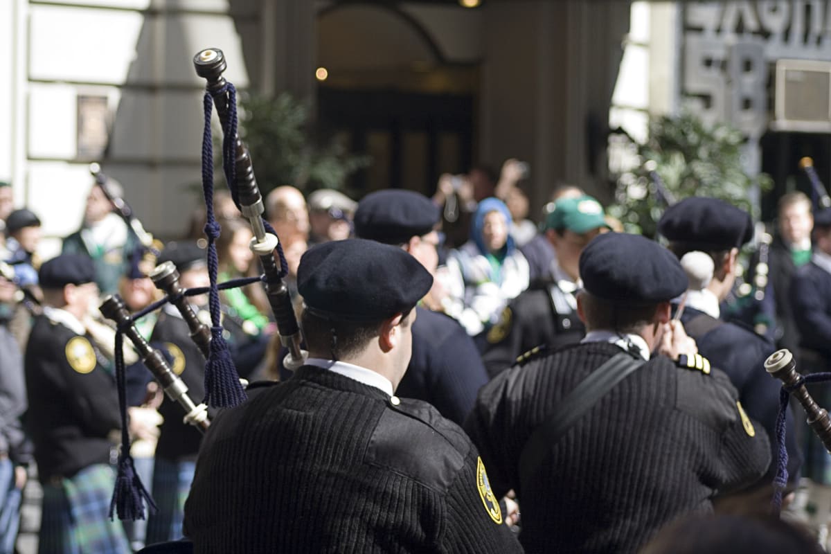 Uilleann pipes being played by men in Irish Kilts at NYC's Paddy's Parade. Crowds watch in the background