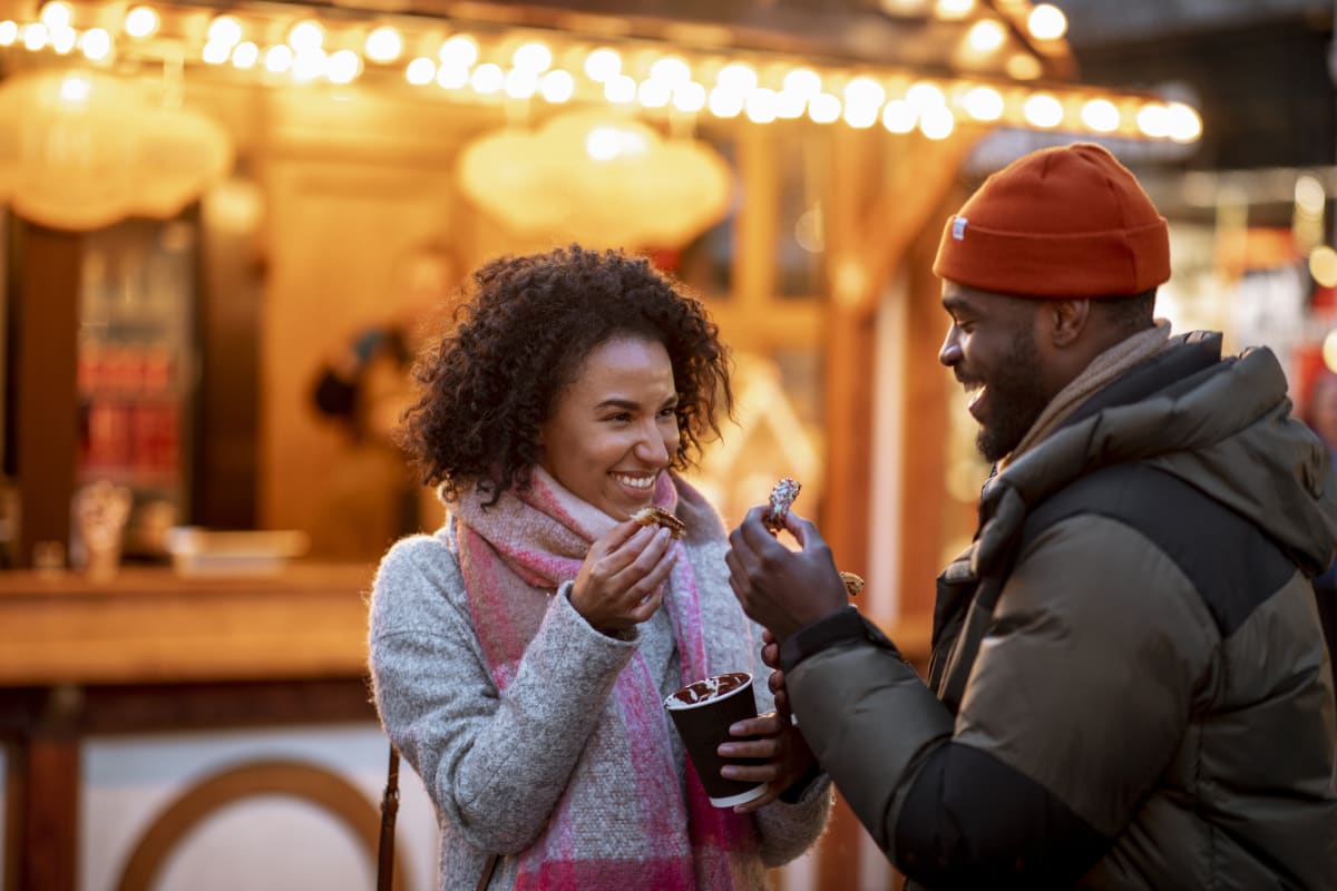 Woman and man smile in front of food truck while eating food