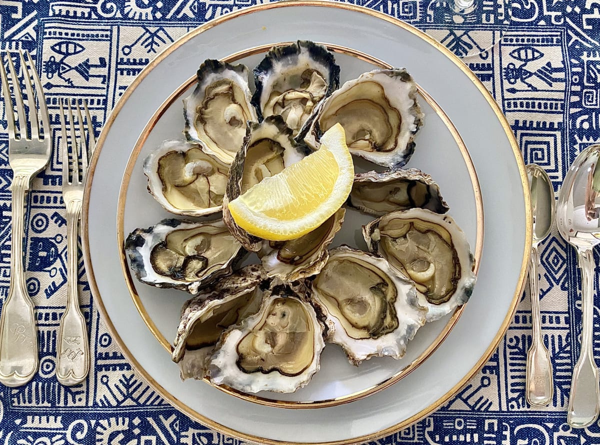 Plate of fresh, raw oysters with a wedge of lemon 