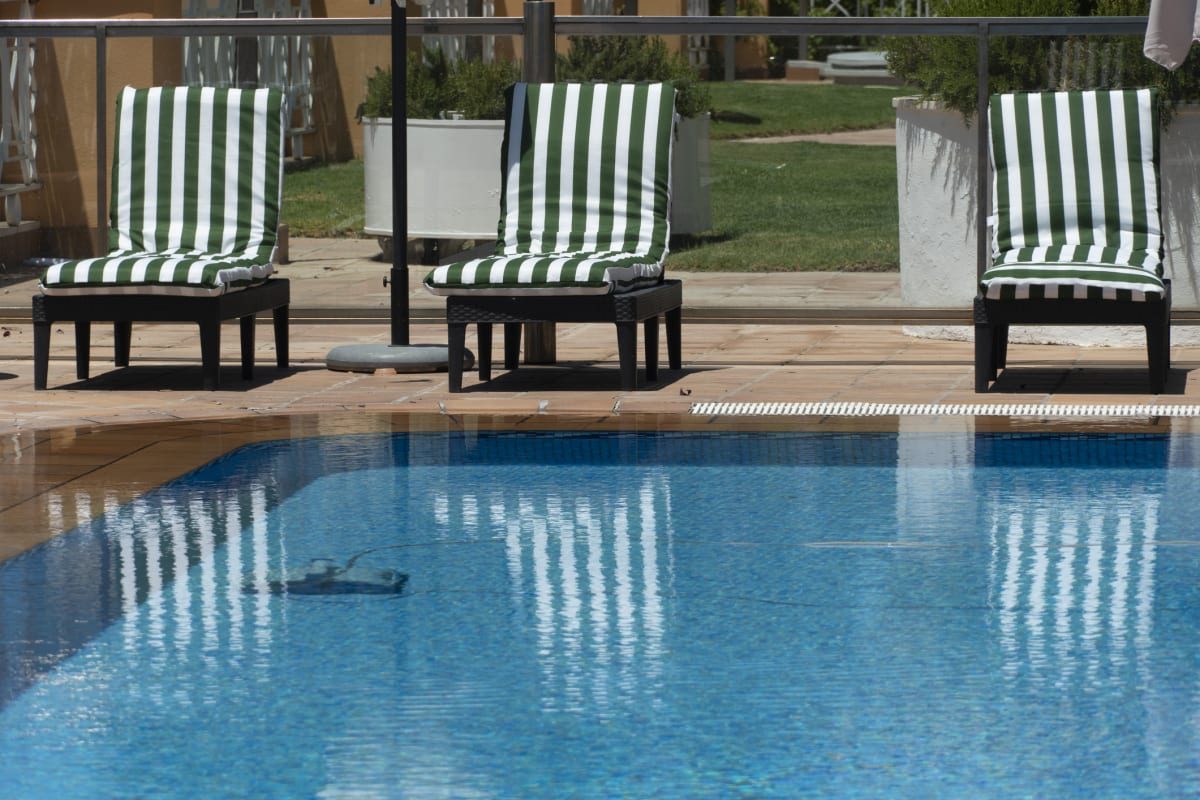 Empty pool with sunbeds behind 