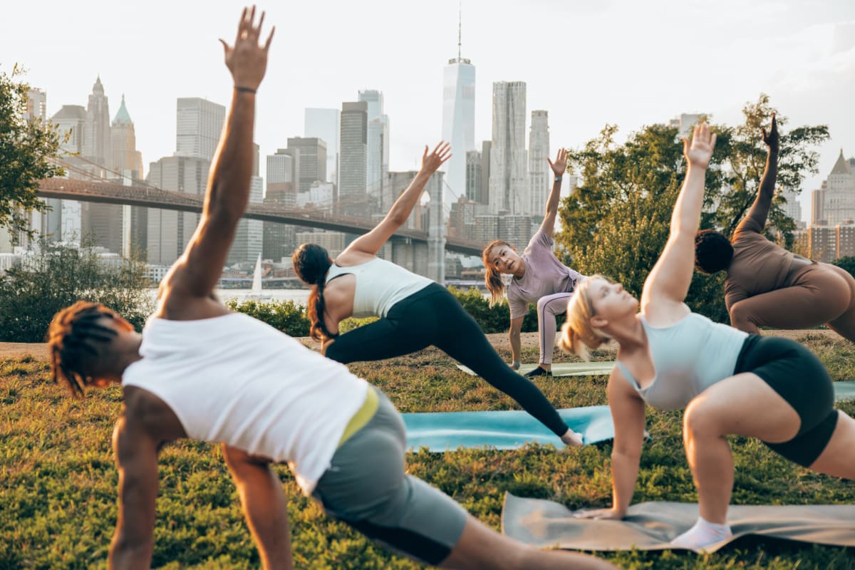 Group yoga session in New York park with New York skyline in background 