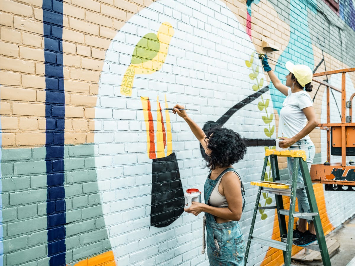 Woman painting street art on brick wall 