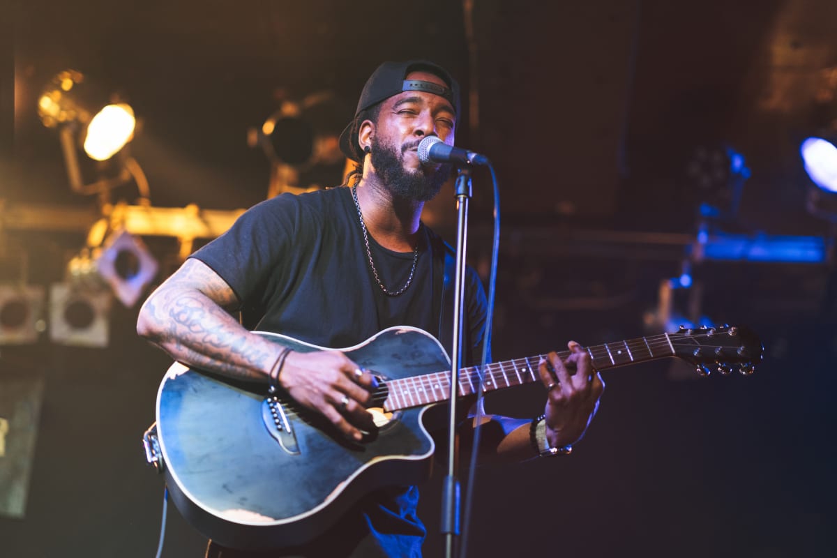 Man plays guitar and sings into microphone on stage 