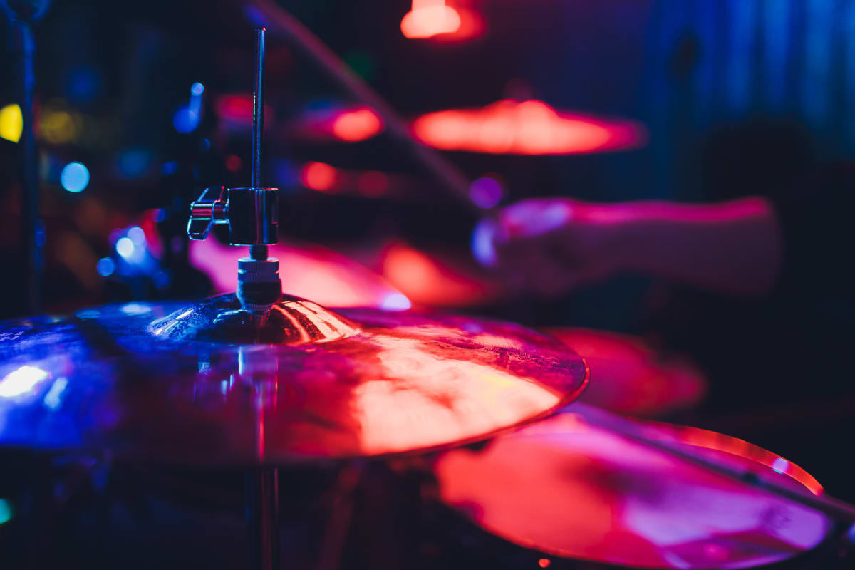 Symbols and drums sets glow red and blue under studio lights