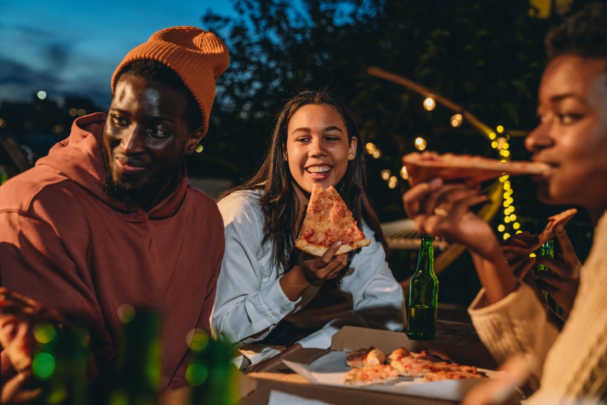 Friends share pizza outdoors