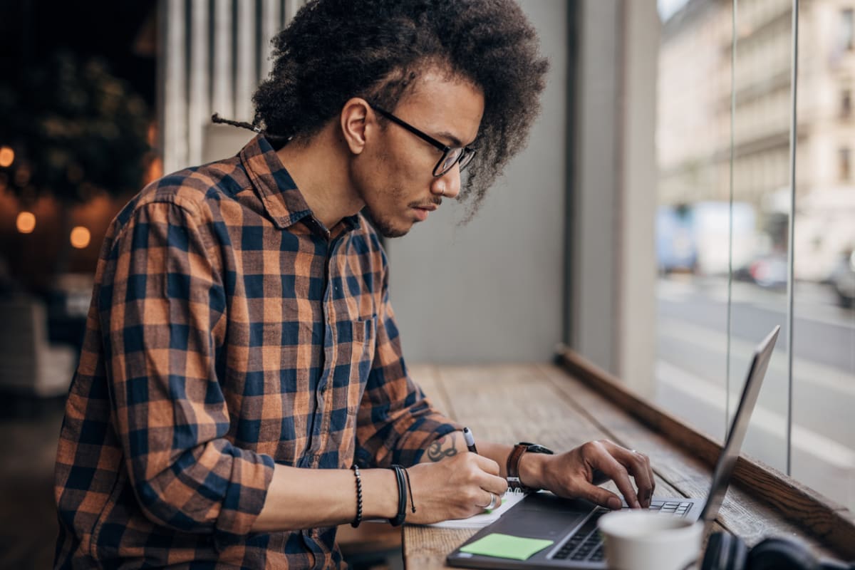 man works from laptop in cafe or bar 