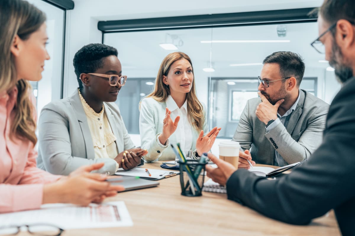 5 people sit around a table in an office environment