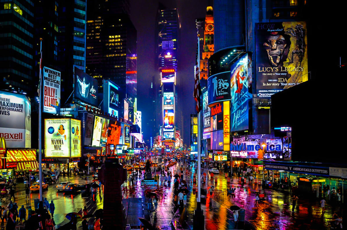 Broadway New York at night with illuminated signs for the individual shows 