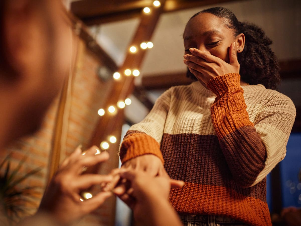 Woman hides her face with her hand while being proposed to