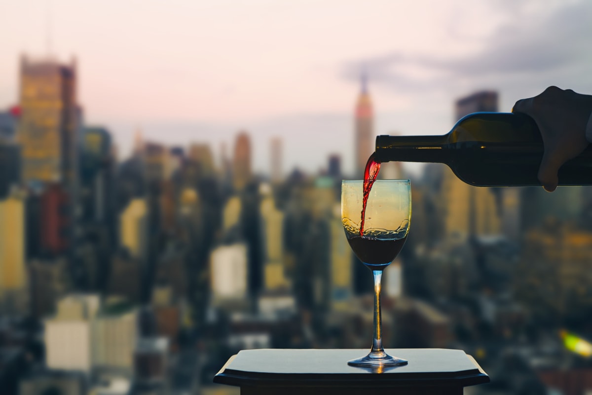 Wine is poured into a glass with an out of focus new york skyline in the background