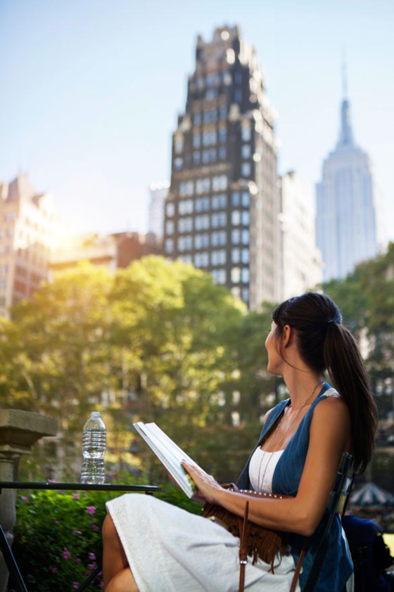 woman-reading-book-in-park-near-empire-state-building