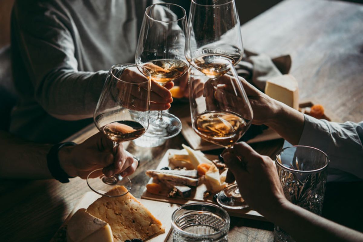 group-of-friends-cheering-with-wine-and-cheese-plates