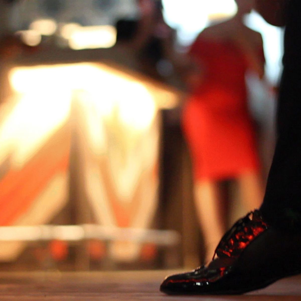 close-up-of-mans-foot-getting-ready-to-dance-with-woman-in-background