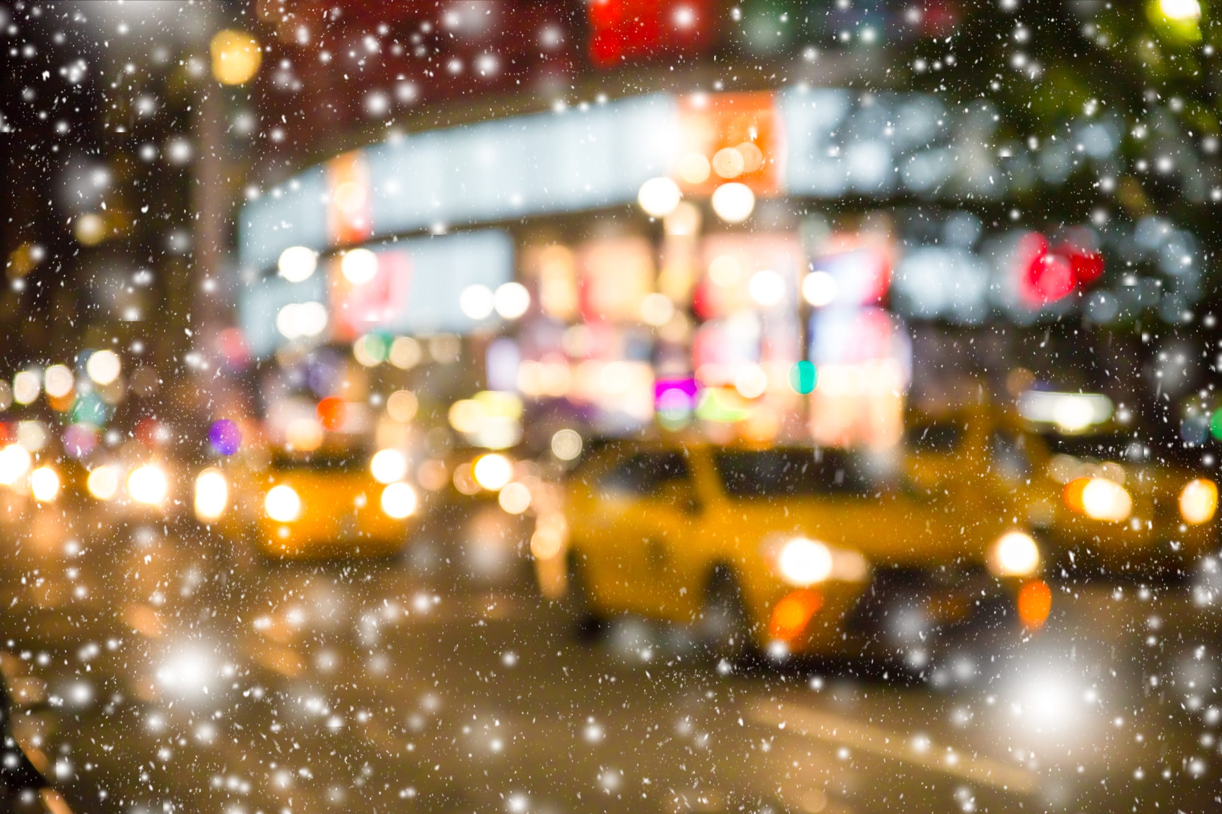 blurry photo of yellow New York cabs on city street in the snow. 