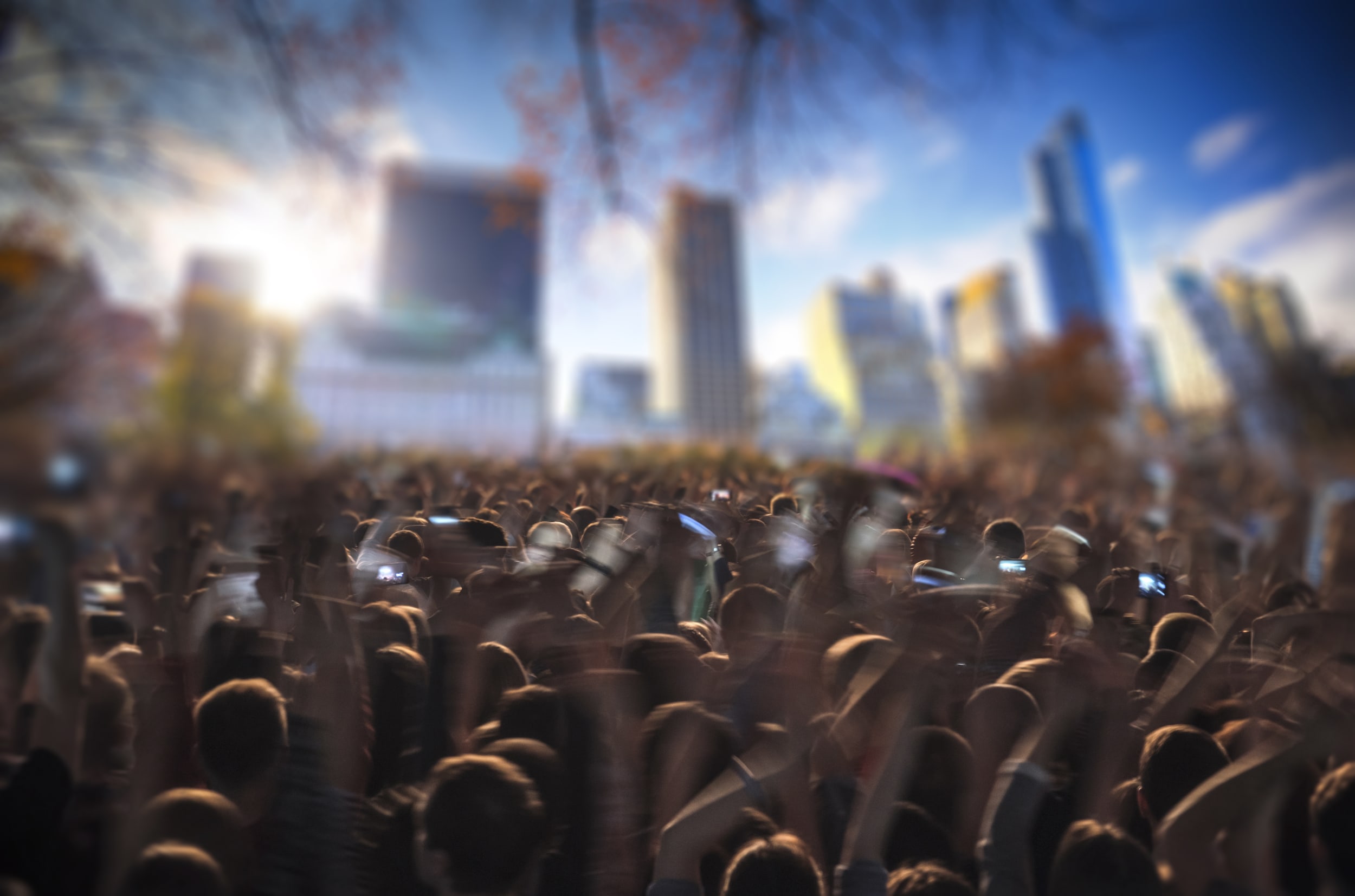 Outdoor concert in new york, crowd in focus dancing and singing, with the new york skyline out of focus in the background