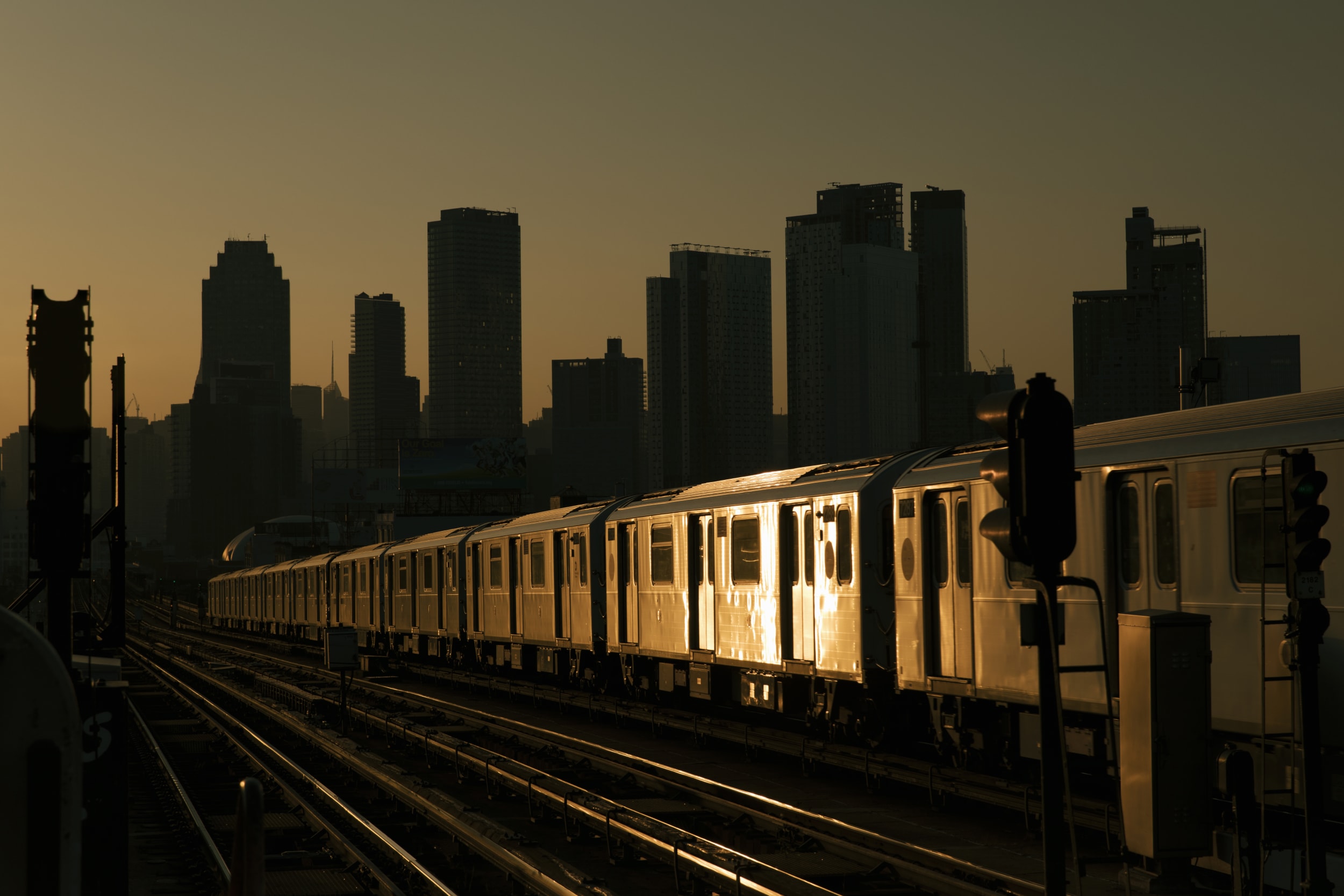 Train heads into New York, with the skyscrapers silhouetted on the sunset  