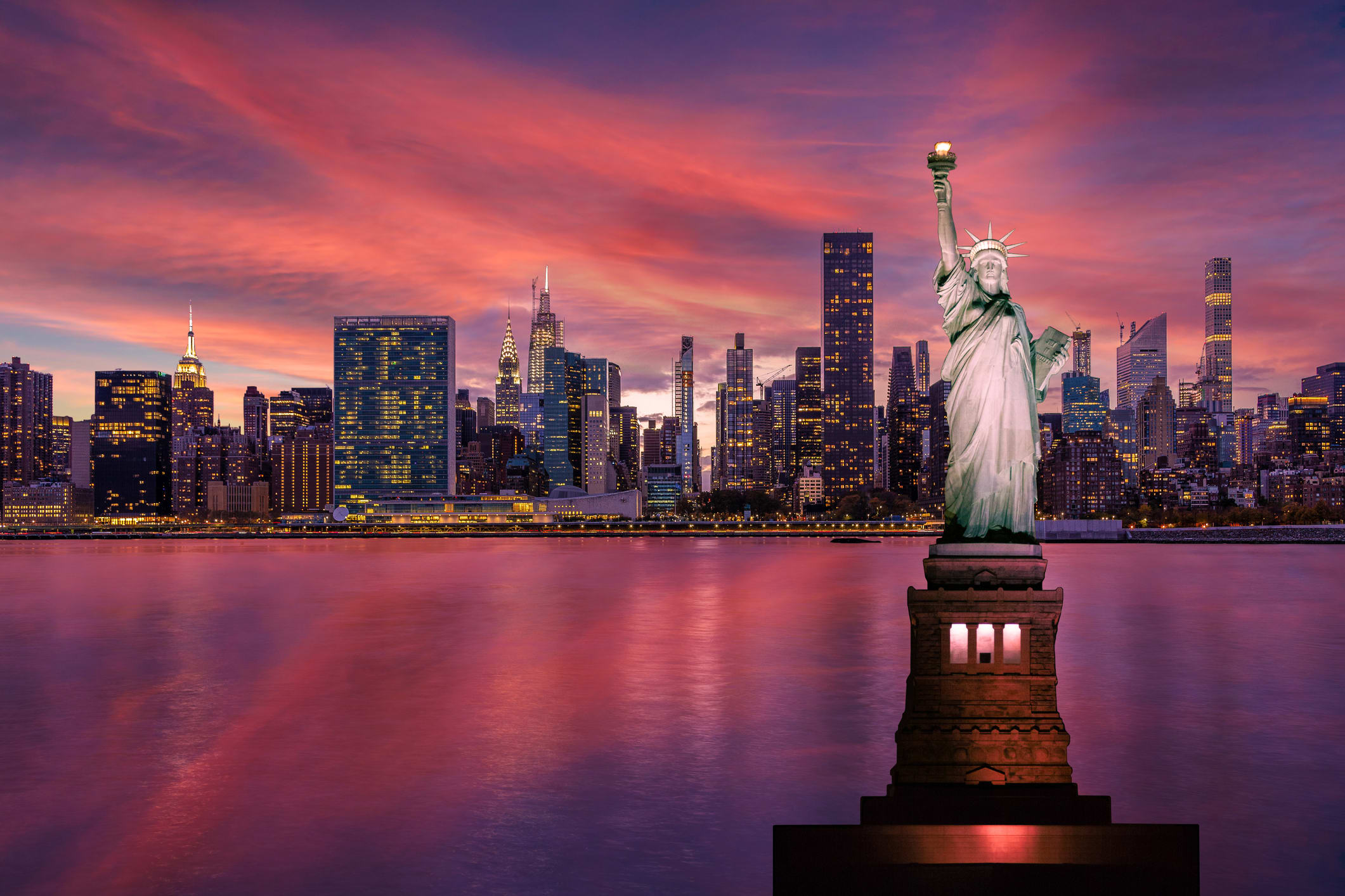 Statue of Liberty in front of New York skyline at sunset